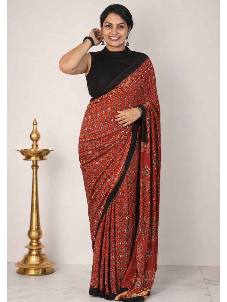 Red Ajrakh modal silk saree by MIZHI featuring intricate mirror work and traditional woven patterns.