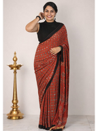 Red Ajrakh modal silk saree by MIZHI featuring intricate mirror work and traditional woven patterns.