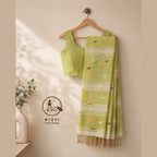 Green MIZHI cotton saree with traditional jamdani pattern, showcasing intricate woven designs and vibrant fabric.