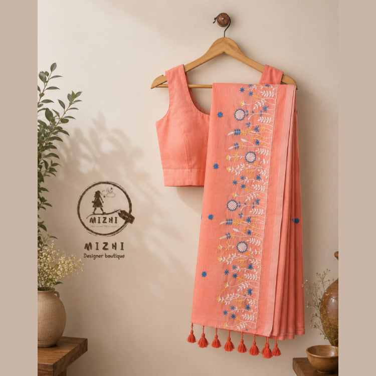 MIZHI embroidered mul cotton saree in peach with intricate embroidery and traditional design, draped elegantly.